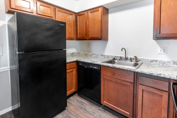 a kitchen with a black refrigerator and wooden cabinets