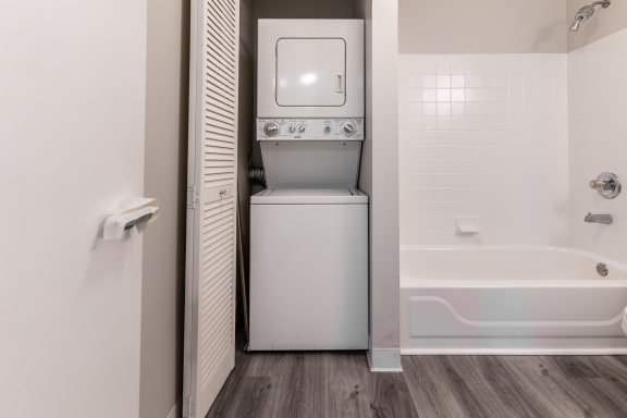 a laundry room with a washer and dryer and a tub in a bathroom