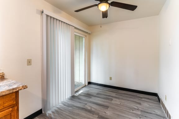 an empty living room with sliding glass doors and a ceiling fan
