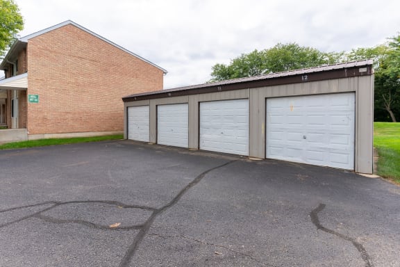 a garage with three white doors and a brick building