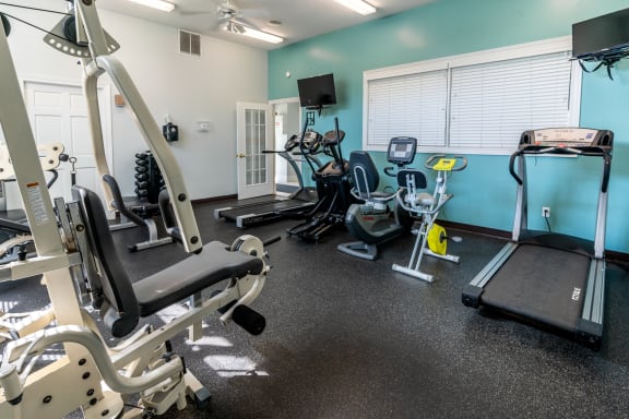 a gym with cardio equipment and weights on the floor