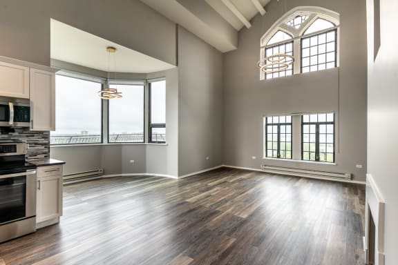an empty living room with a kitchen and a large window