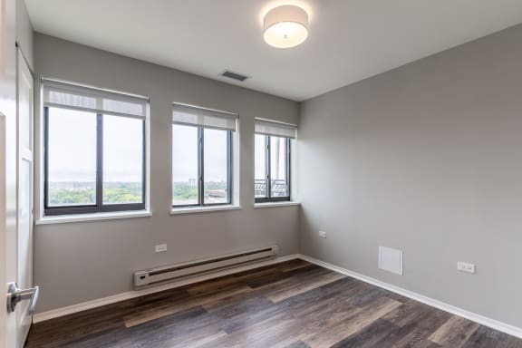 an empty living room with three windows and wood flooring