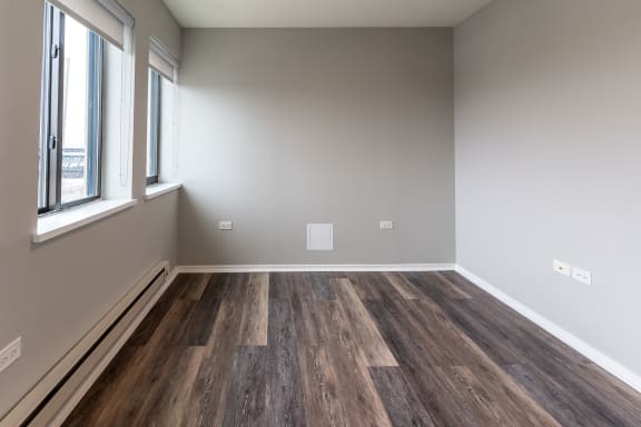 an empty room with wood flooring and a window