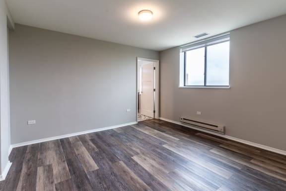 an empty living room with wood flooring and a window