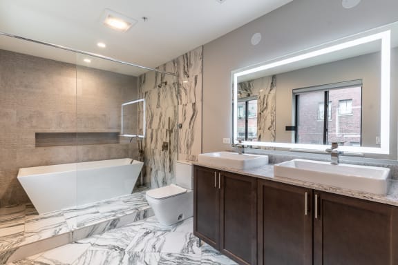 a bathroom with a tub and two sinks and a mirror