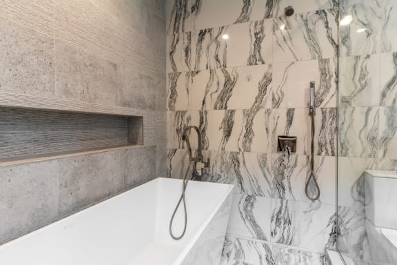 a marble bathroom with a tub and shower and a sink