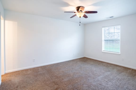 an empty room with a ceiling fan and a window
