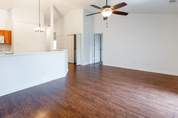 an empty living room with wood flooring and a ceiling fan
