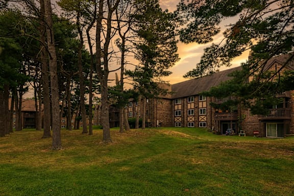A large building surrounded by trees with a grassy field in front.