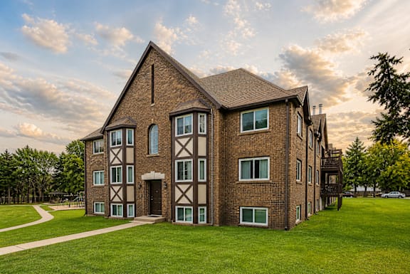 A large brick building with a green lawn in front.