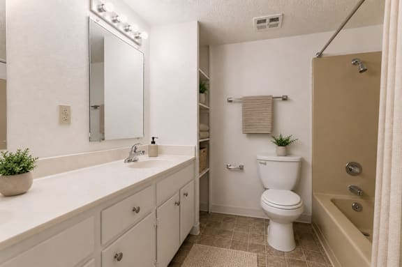 A white toilet sits in a bathroom next to a sink and a bathtub.