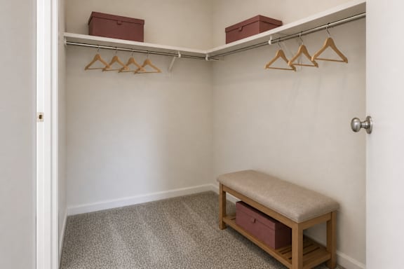 A small closet with a bench and hangers.