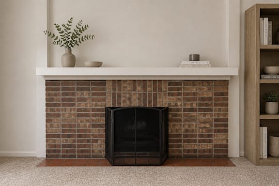 A black fireplace with a plant on top of a mantle.
