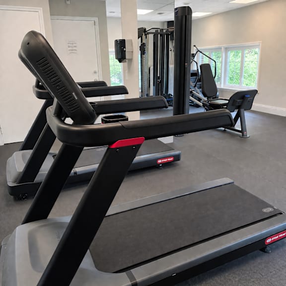 A treadmill in a gym with a red light on the side.