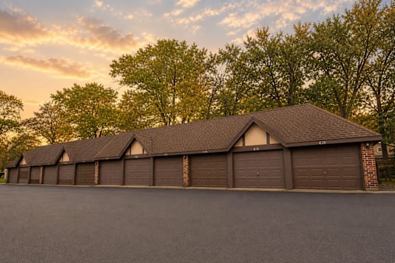 A row of houses with garages are in front of trees.