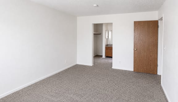 A room with a carpeted floor and a wooden door.