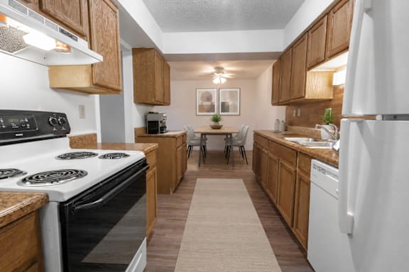 A kitchen with white appliances and wooden cabinets.