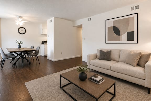 A living room with a couch, a dining table, and a painting on the wall.