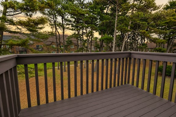 A wooden deck overlooks a grassy area with trees.