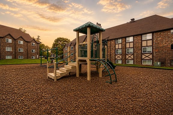 A playground with a green slide and wooden steps.