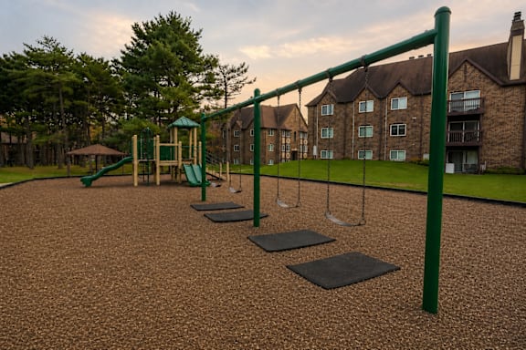 A playground with a green swing set and a brown ground.