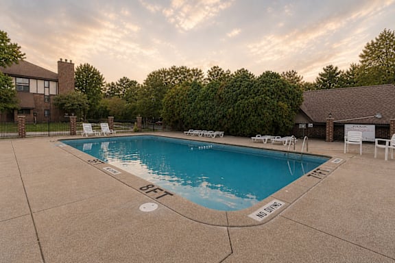 A large outdoor swimming pool surrounded by trees and a house.