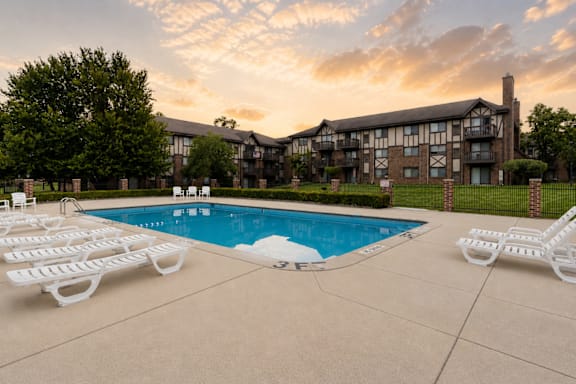 A pool surrounded by white lounge chairs and a building in the background.