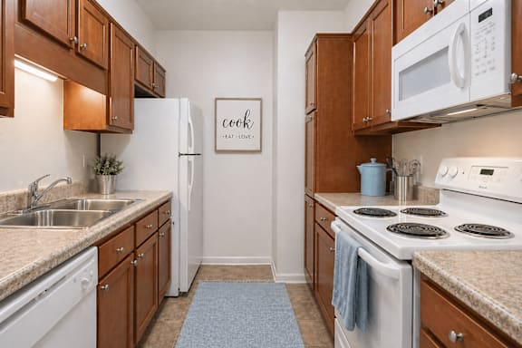 A kitchen with white appliances and wooden cabinets.