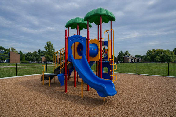 A playground with a blue slide and a green canopy.