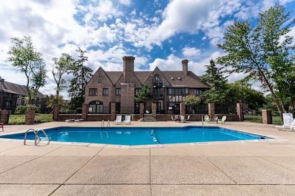 a swimming pool in front of a large brick house with a pool