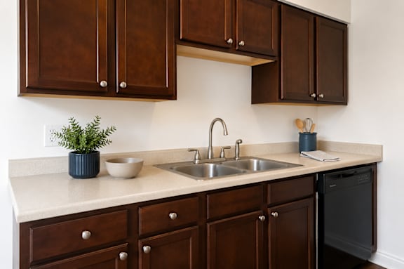 A kitchen with brown cabinets and a black dishwasher.