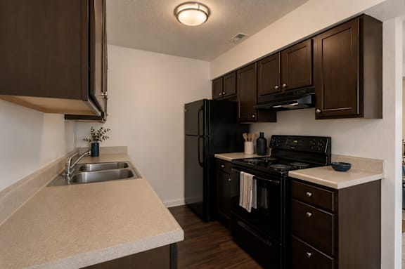 A kitchen with brown cabinets and black appliances.
