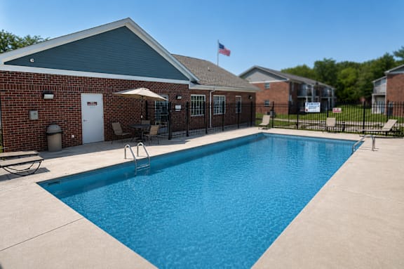 A swimming pool in front of a brick building with an American flag.