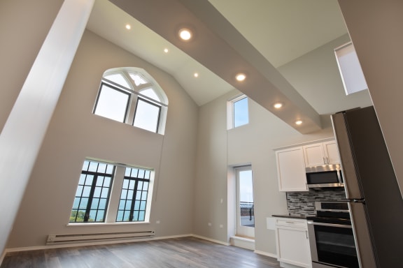 a kitchen and living room with high ceilings and windows
