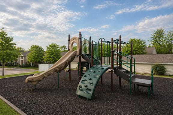 A playground with a green slide and a brown slide.