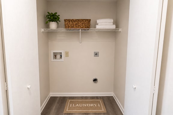 A small laundry room with a basket and towels on the shelf.