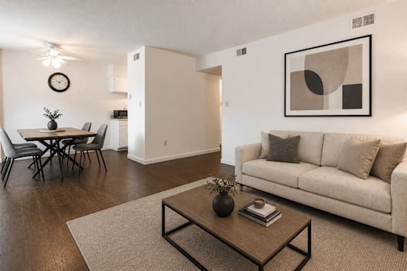 A living room with a couch, a dining table, and a painting on the wall.