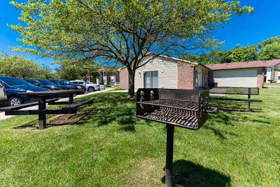 a grill and picnic table in the grass in front of a house at Creekside Square Apartments, Indianapolis, IN 46254