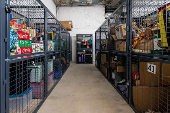 A storage room with aisles of wire mesh cages filled with boxes and other items.