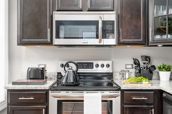 Kitchen with white appliances and black cabinets and a white stove and microwave at Somerset Place Apartments, Chicago, Illinois