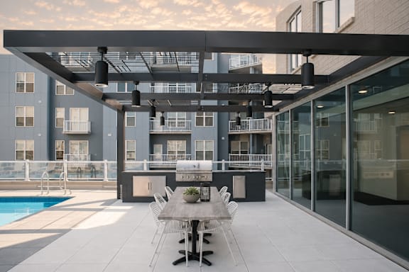 A modern outdoor dining area with a pool and a building in the background.