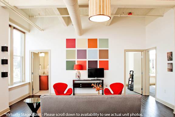 A living room with a grey couch and a red chair.