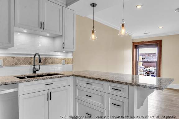 A kitchen with a marble countertop and white cabinets at The Knights @ 506 Delaware Apartments, Buffalo
