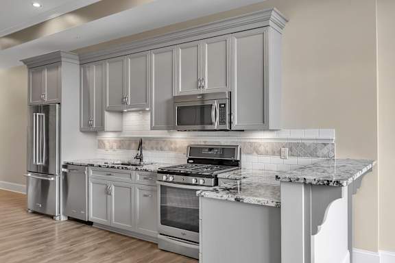 A modern kitchen with a marble countertop and stainless steel appliances.