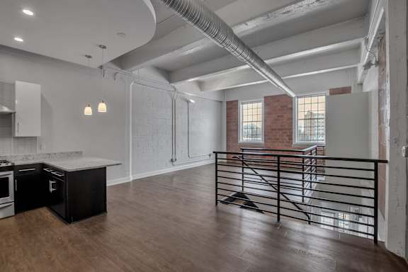 Open loft kitchen with railing overlooking lower level at The Lofts at Elk Terminal Apartments, Buffalo