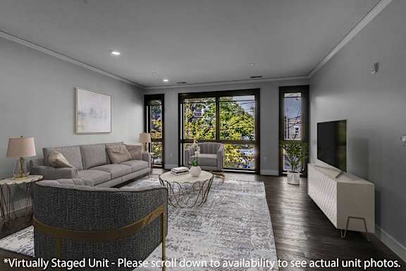 a living room with a grey couch and a tv at Nineteen North Apartments , Buffalo