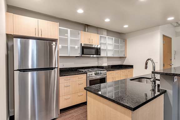Modern kitchen with black granite countertops and island at The Lofts at Elk Terminal Apartments, New York