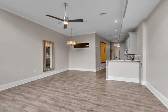 A spacious room with a ceiling fan and a chandelier.