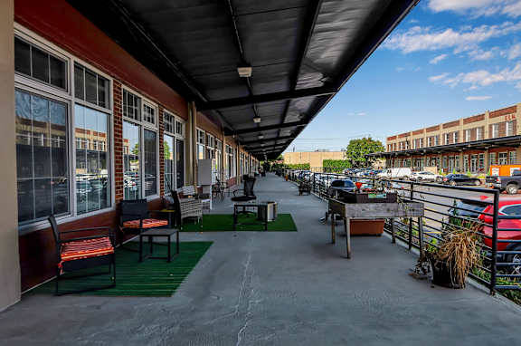 Covered outdoor patio with seating areas and parking view at The Lofts at Elk Terminal Apartments, New York, 14204